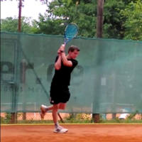 Keen employee on a tennis court swinging a racket